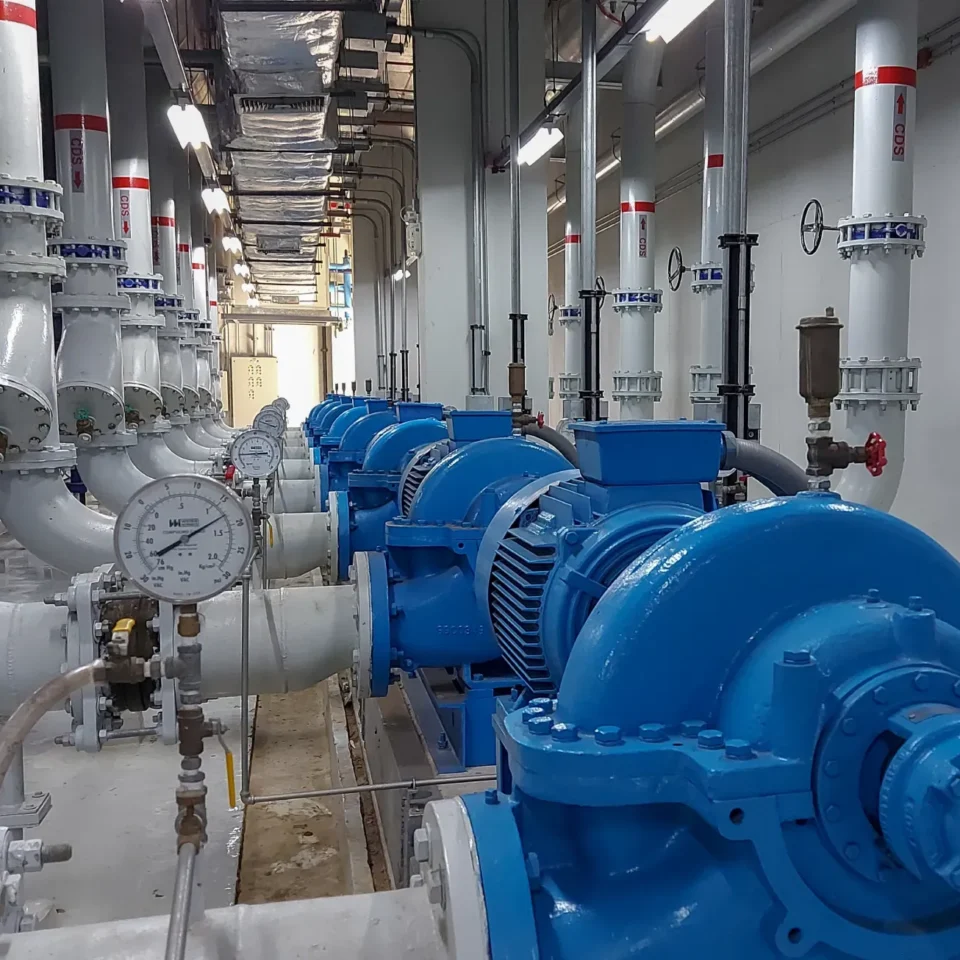 Industrial pumping station with blue centrifugal pumps and high-pressure piping for water distribution.