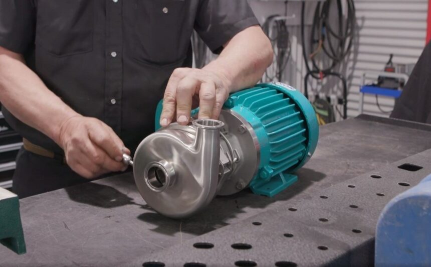 Technician performing maintenance on an electric pump in a workshop setting.
